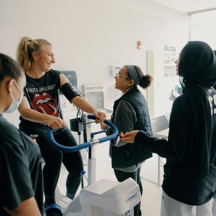 Student on exercise bike taking vitals